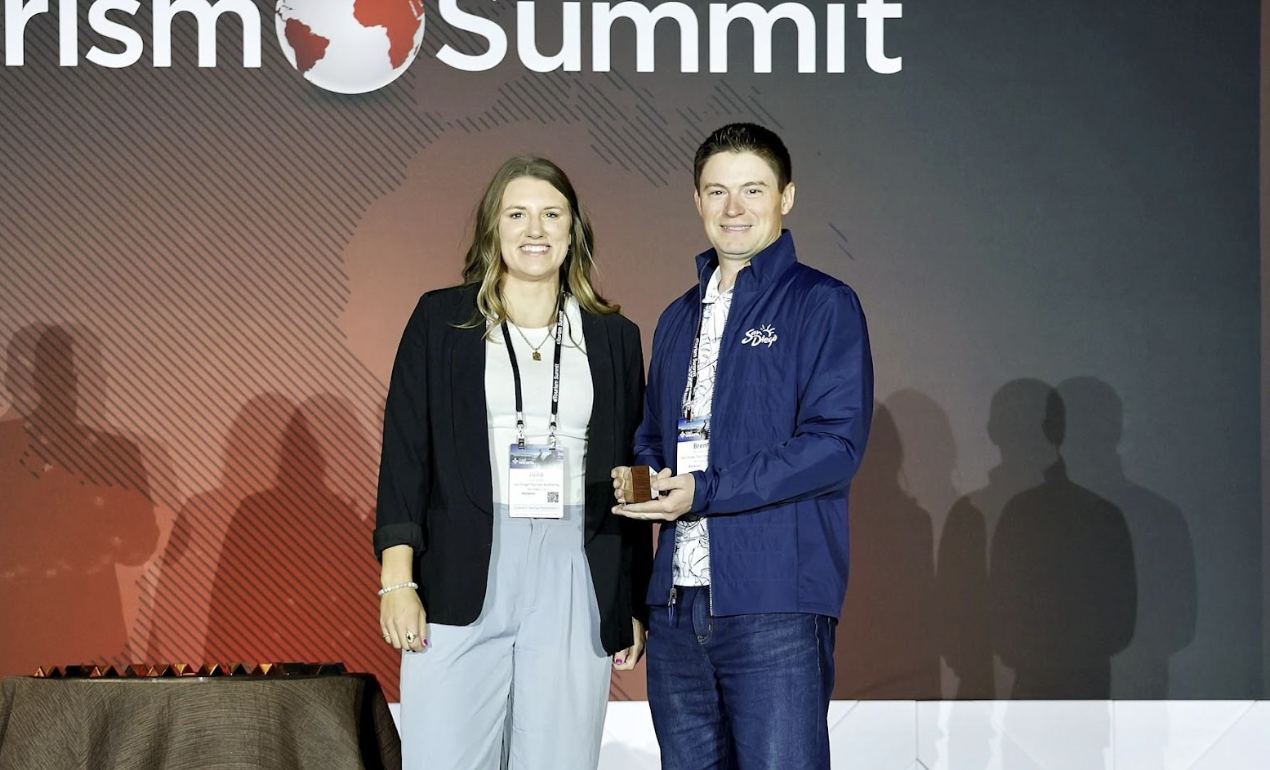 A man and a woman standing on stage at eTourism Summit holding their eTSY Award.