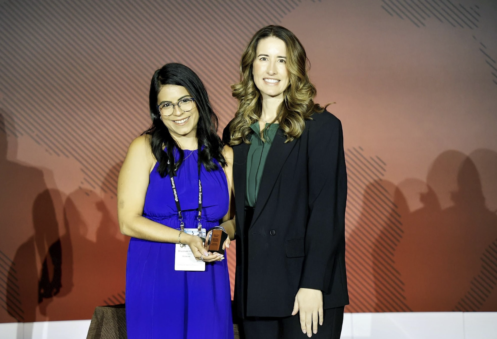 Two women on stage at eTourism Summit smiling and holding their eTSY Award.