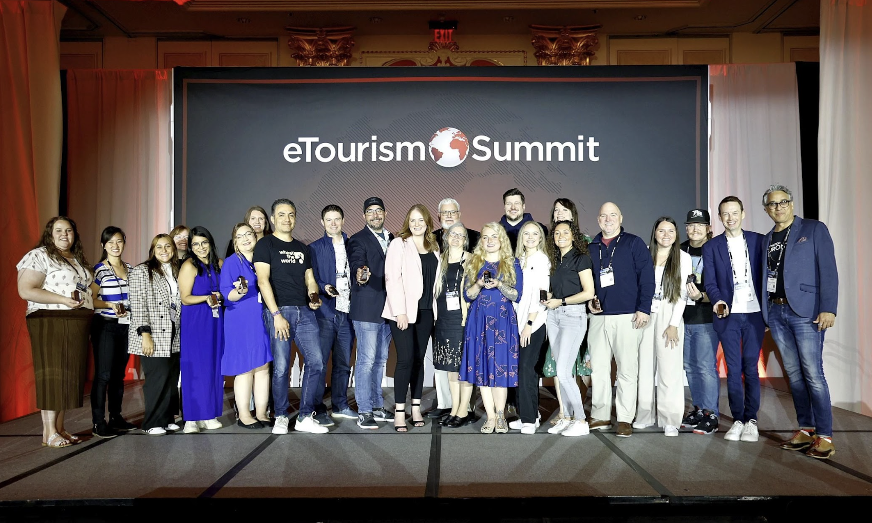 A group of professionals on stage at eTourism Summit smiling and holding their eTSY Awards.