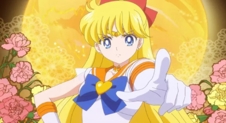 Sailor Venus points at the screen, her tone stern. Behind her, pink and yellow flowers bloom