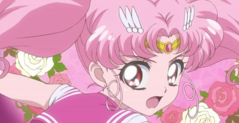 Chibi Moon looks over her shoulder. She is surrounded by pink and white roses.