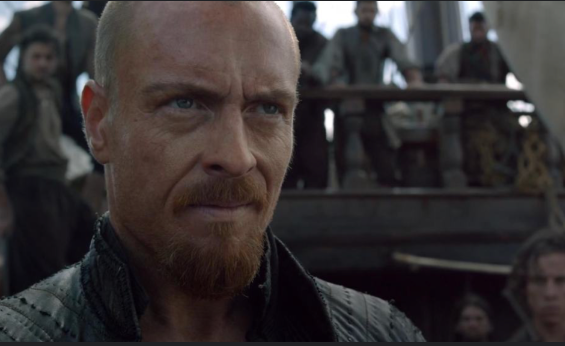 Captain James Flint stares seriously after an unknown person off screen. His mouth turned up in a confused grin.