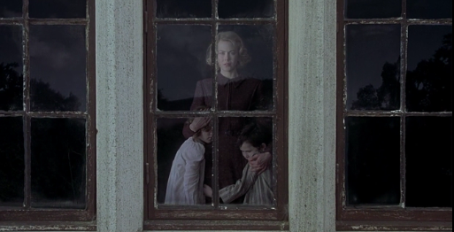 Grace (Nicole Kidman) shields her kids as they all stare out the window, afraid of whatever is on the other side. 