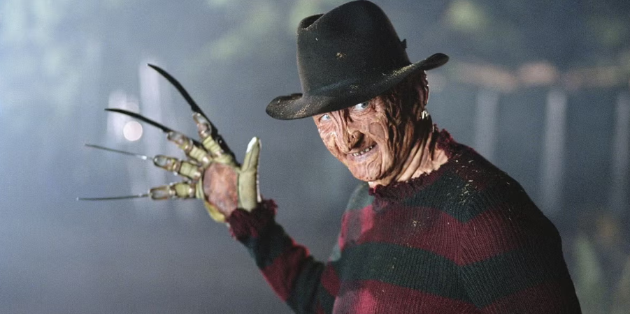 Freddy, smiles his terrifying smile, waving his gloved hand menacingly.