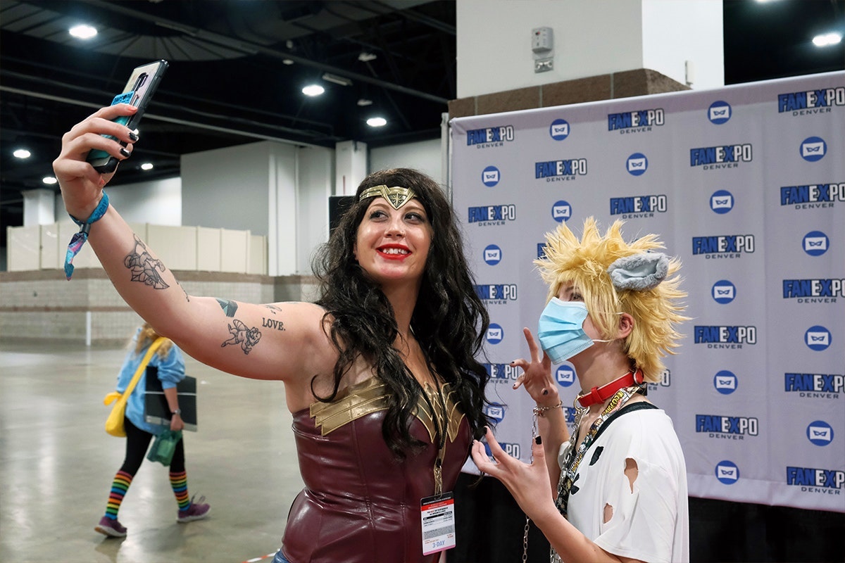 A wonder woman & an Anime cosplayer pose for a selfie together taken by Wonder Woman