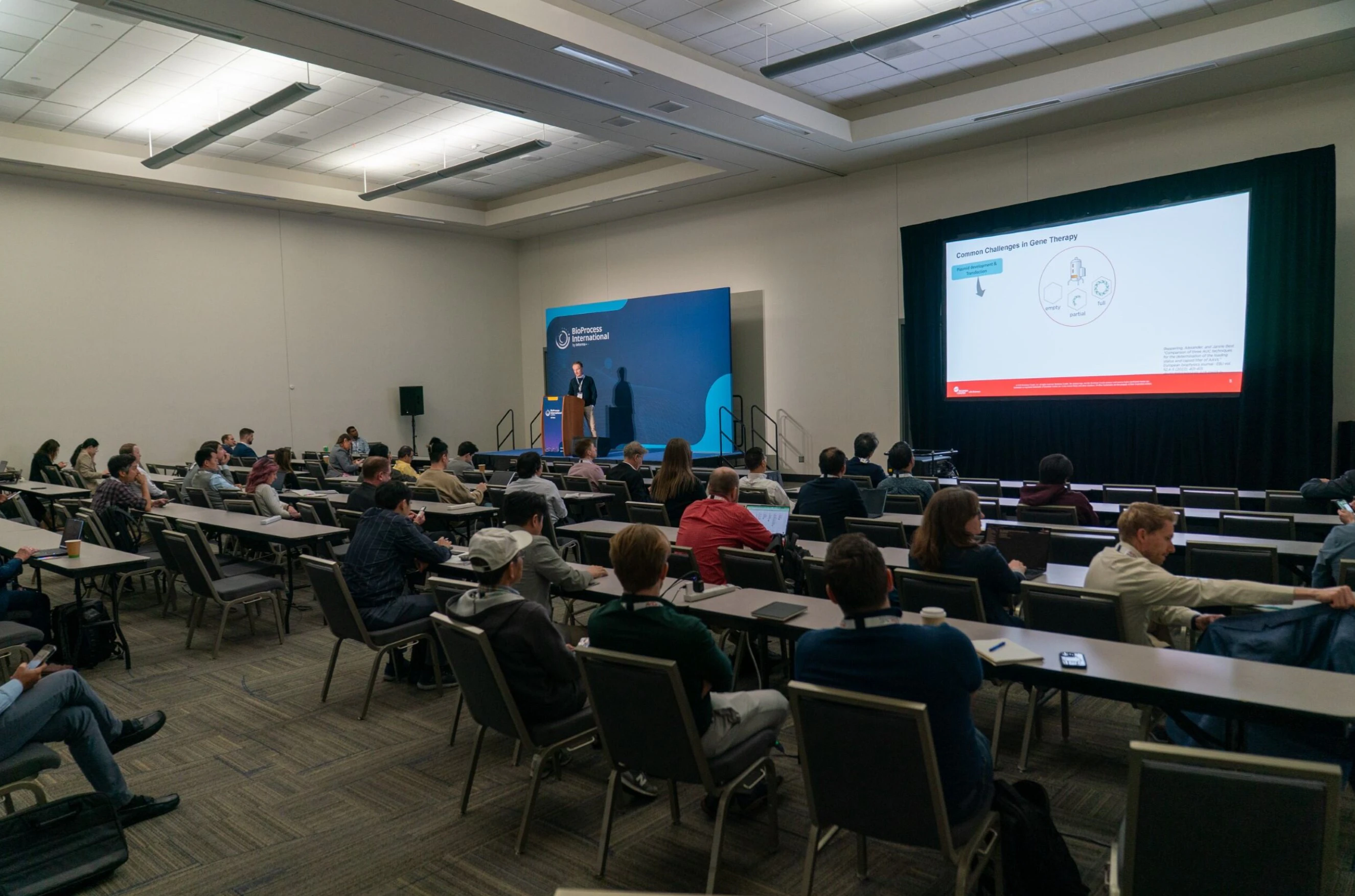 A conference room with attendees and a main speaker on stage at BPI West