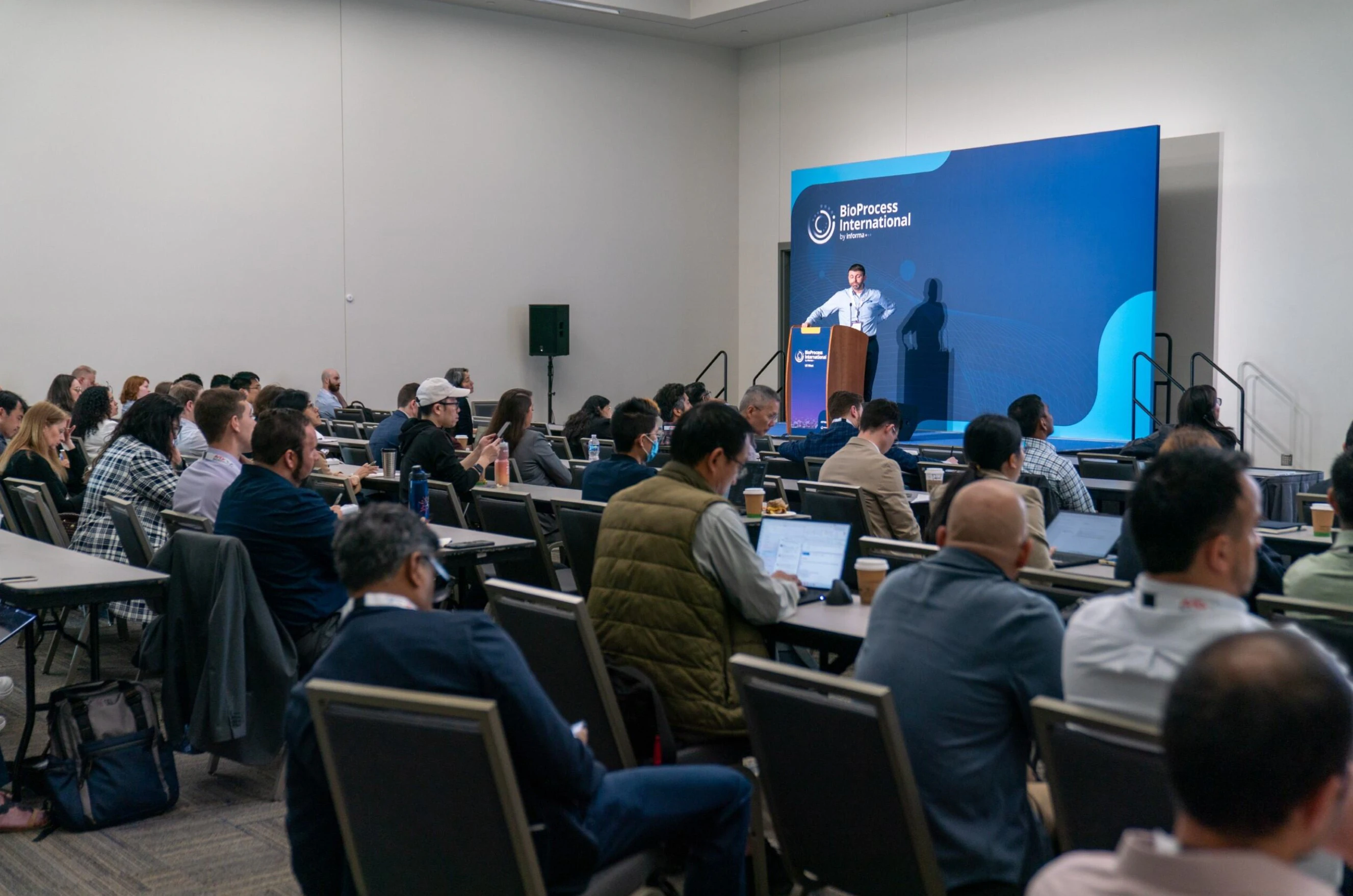 A panel discussion on stage with the host standing by a podium asking a question at BPI West