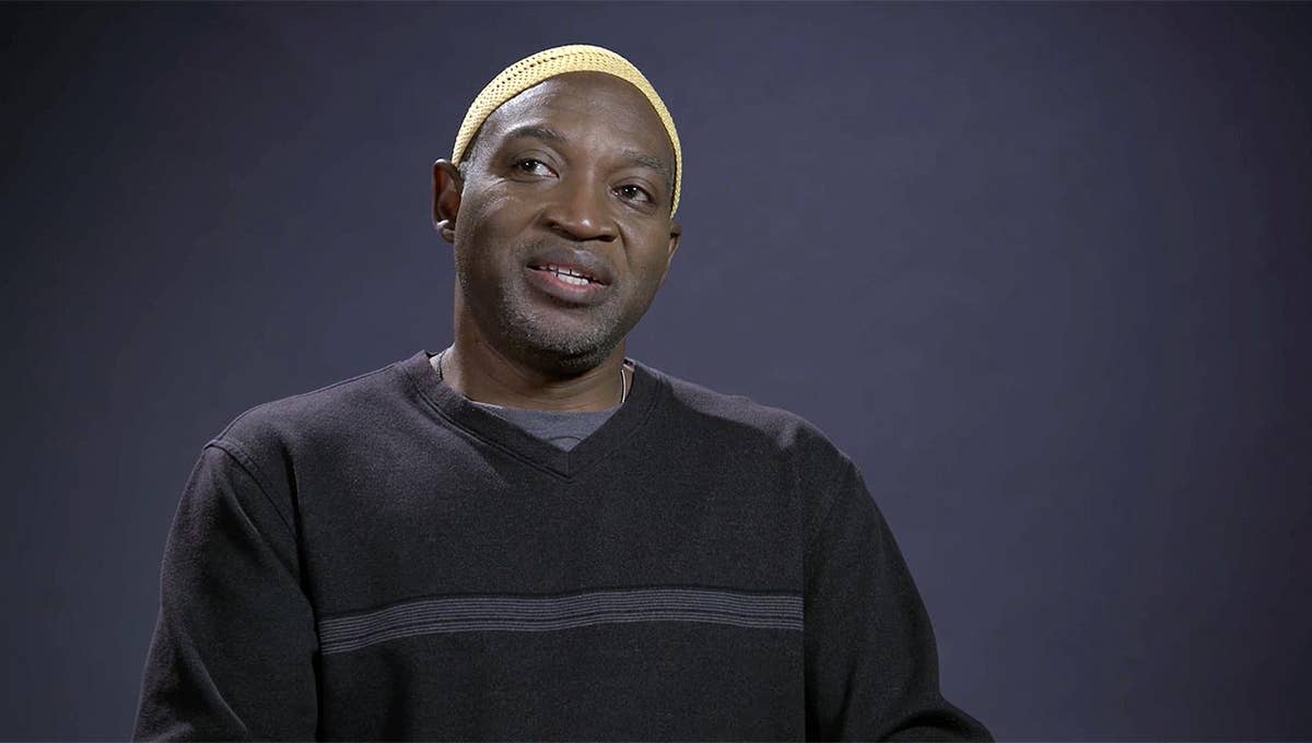 Brian Stelfreeze wearing a grey sweater and yellow beanie looks off to the side