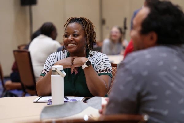 A student smiles while participating in the Troubleshooting and Problem-Solving Bootcamp alongside fellow IT professionals.