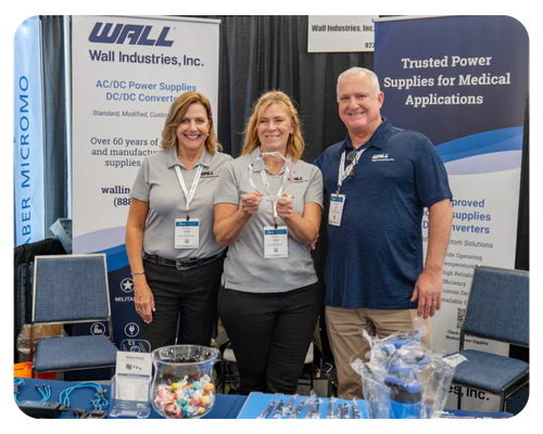 Three individuals stand beside a table showcasing their products