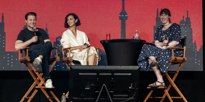 Left to right: Ben McKenzie, Morena Baccarin, moderator Maggie Lovitt. The three are sat in director's chairs - Maggie smiles at the audience, Ben answers a fan's question as Morena looks at him with a warm smile.