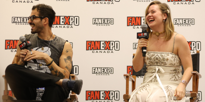 Voices of Denji and Power from Chainsaw Man, Ryan Colt Levy and Sarah Wiedenheft, sit in directors chairs. They are seated in front of a white FAN EXPO Canada backdrop. Both are laughing as they answer a fan question.