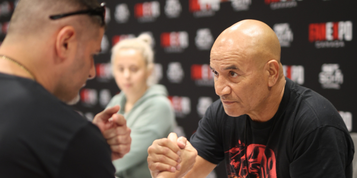 Temuera Morrison joins hands with a fan as the fan speaks. They share a look as Temuera listens intently.