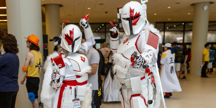 A pair of Mandalorians pose, blasters forward. Their colouring is red and white, and there are half maple leaves on their helments