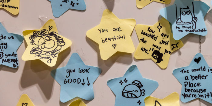 Fans wrote affirmations and posted them on the wall of the Carmico booth - the notes are written on star shaped sticky notes and they read "The world is a better place because you're in it", "you are beautiful just the way you are", "you look good", "you look beautiful". There is also an assortment of cute illustrations.