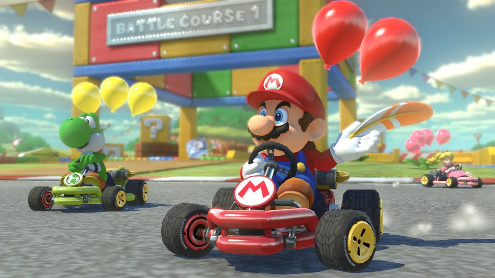 A still from Mario Kart featuring Mario and Yoshi in their karts, closely followed by Peach