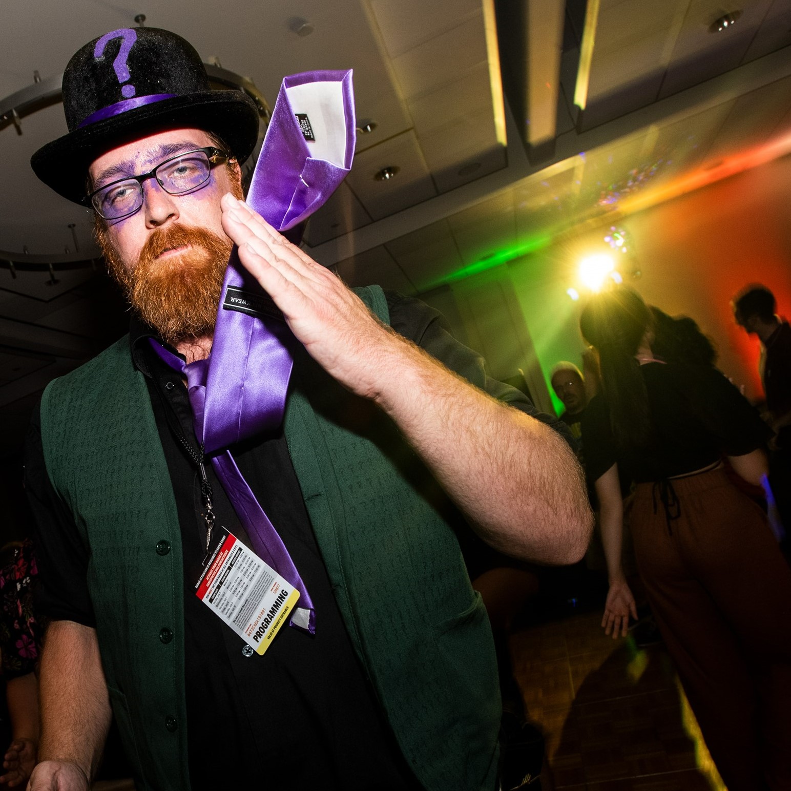 Fancy Riddler in a green vest and purple silk tie who is dancing.