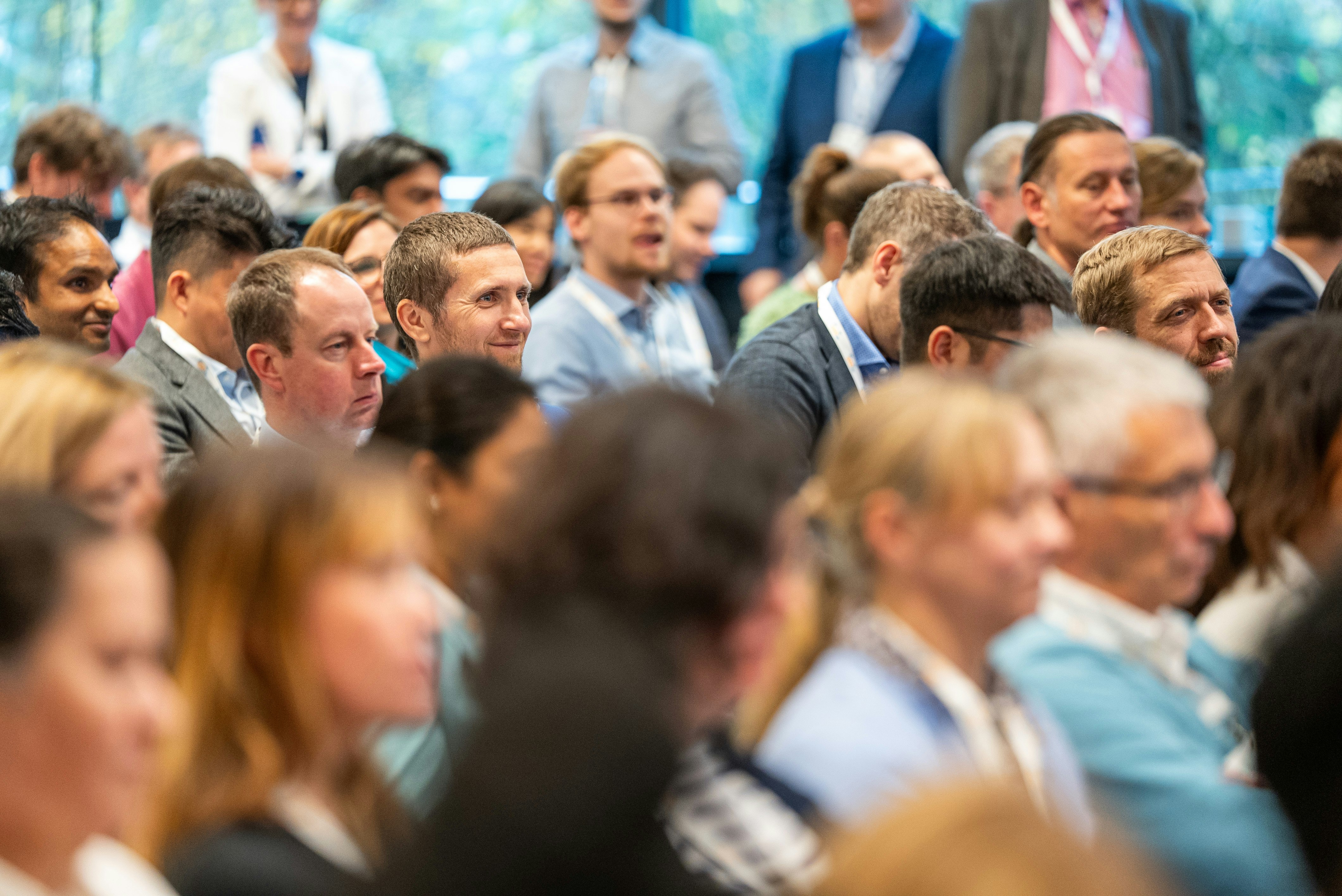 Attendees sit during a conference session with focus on a man smiling