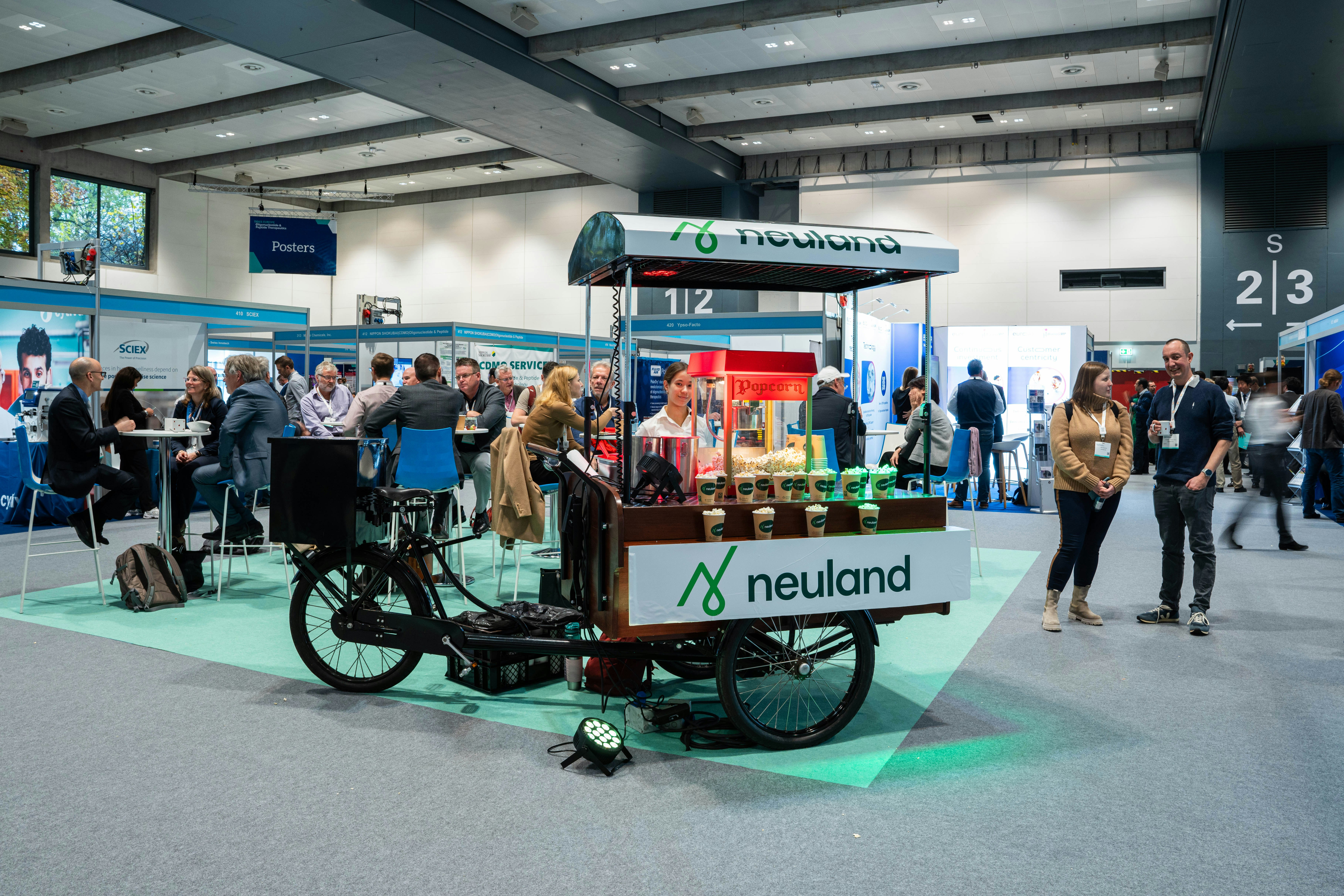 Neuland branded coffee stand sitting on bicycle wheels in the exhibit hall.