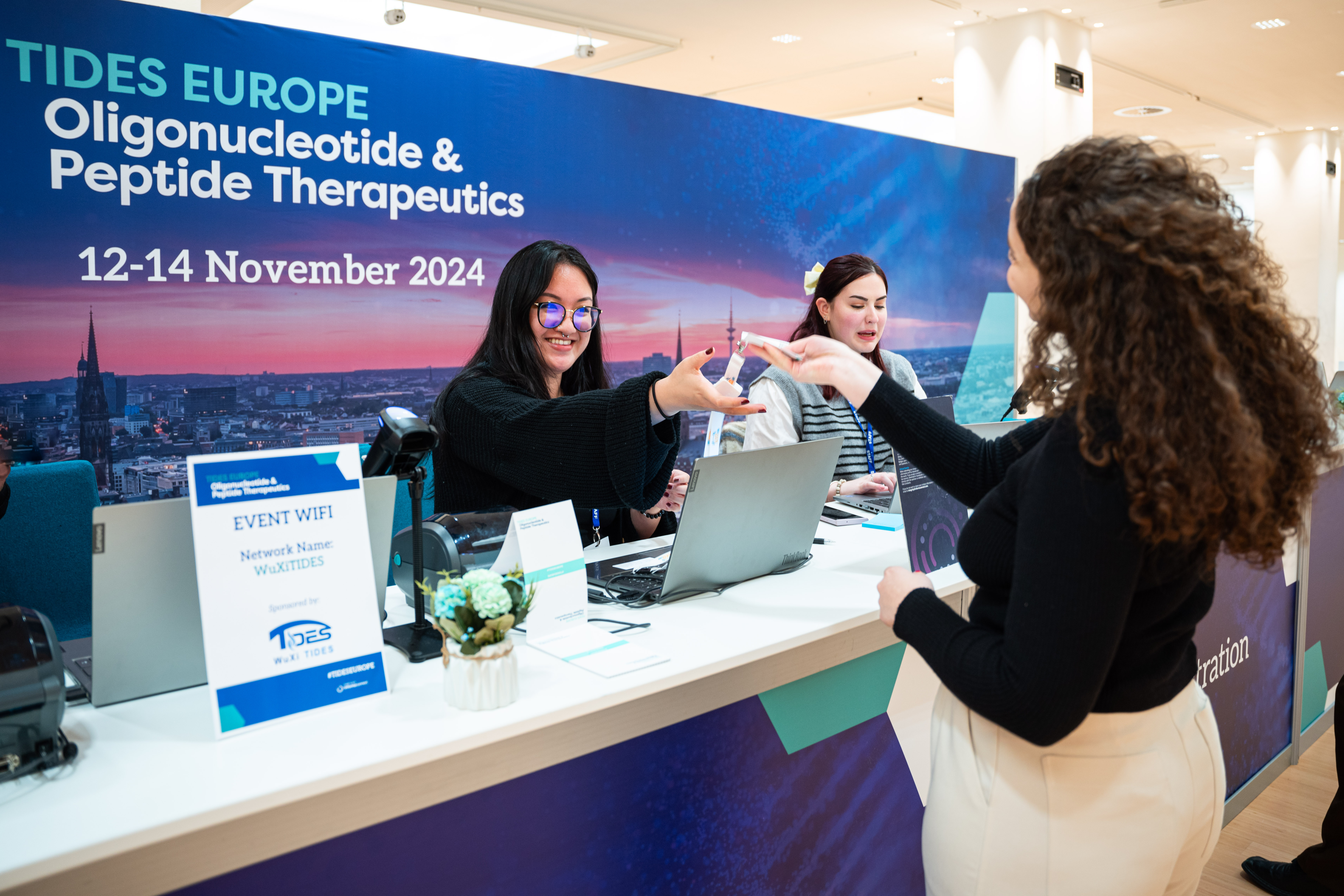 Registration desk at TIDES Europe with an attendee collecting their page from a staff member