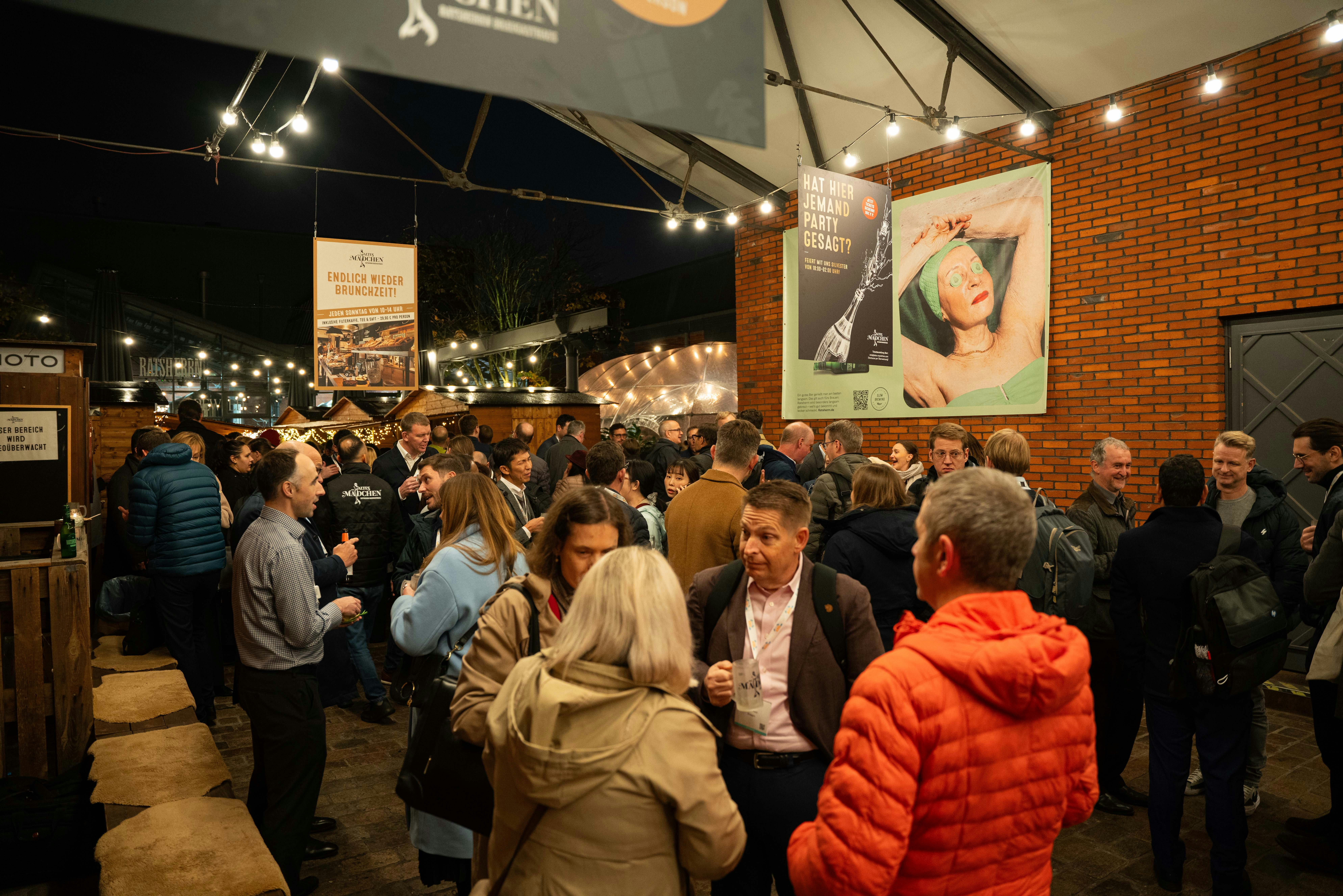 A crowd stands outside at night in various conversations.