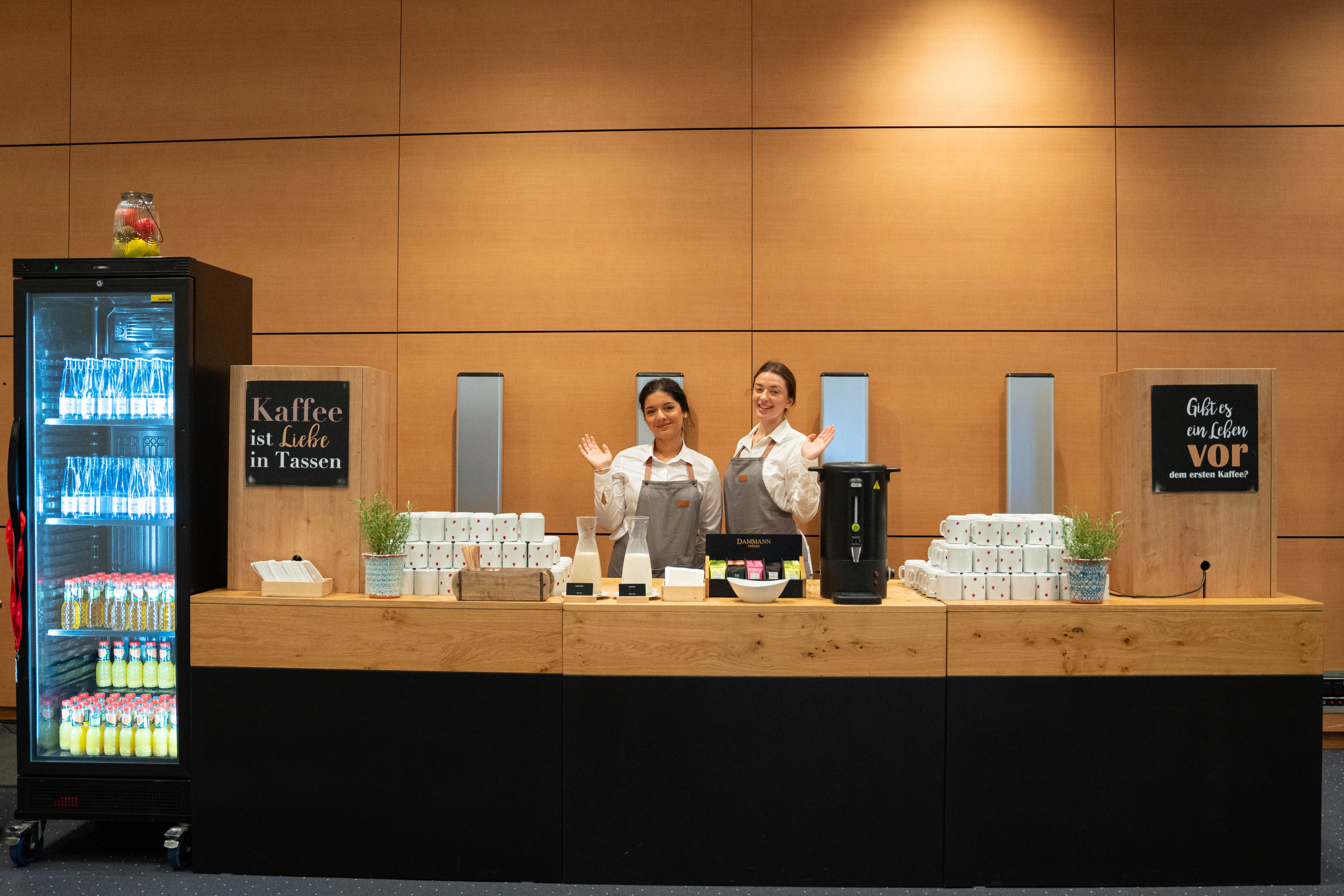 Two coffee stand staff workers wave to the camera.
