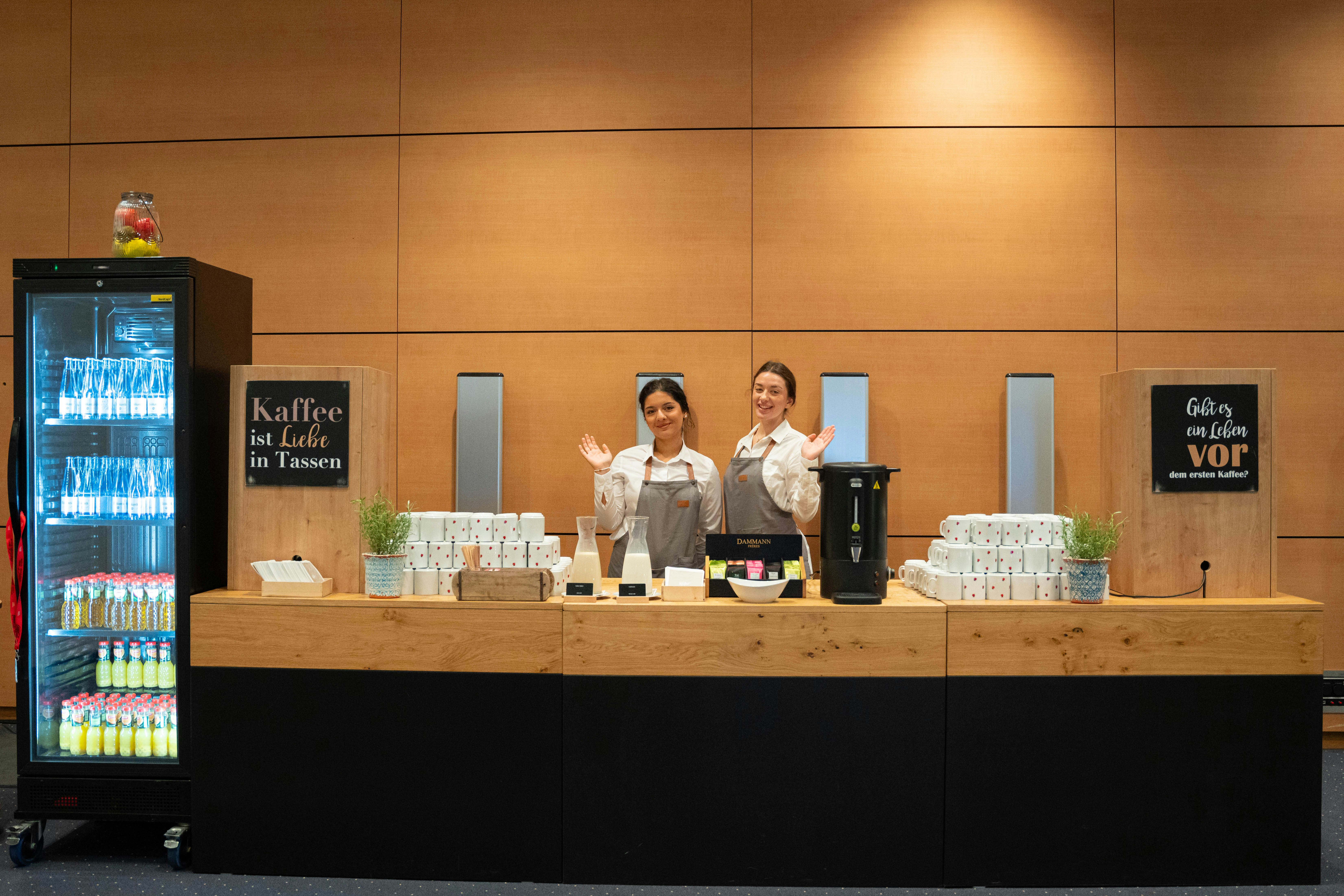Two coffee stand staff workers wave to the camera.