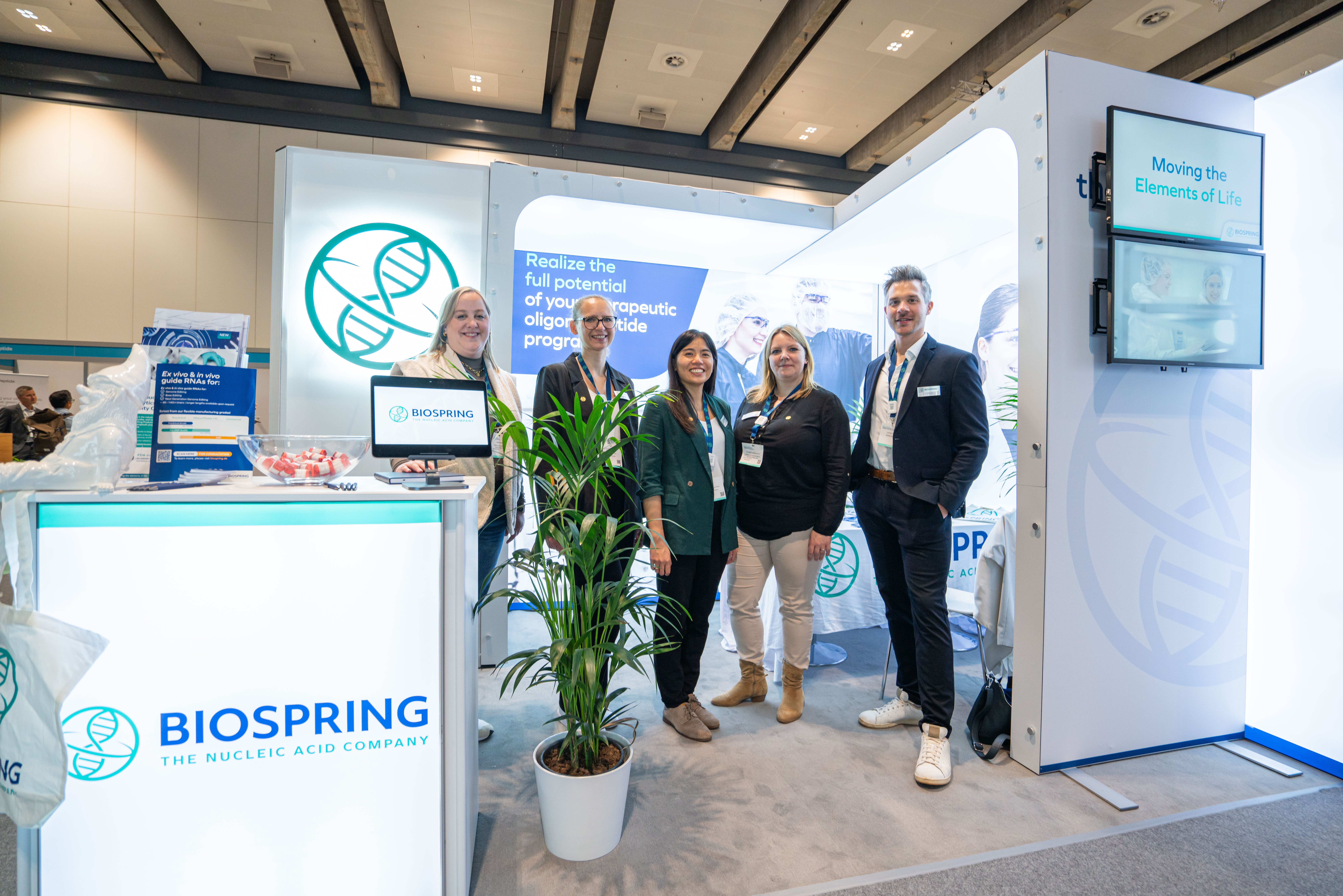 Five BIOSPRING colleagues pose for the camera in front of their stand.
