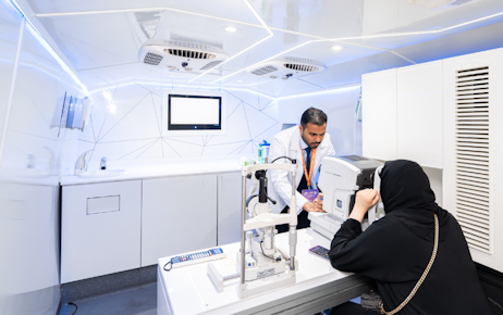 Emirati exhibitor giving documents to Emirati men at Tawdheef