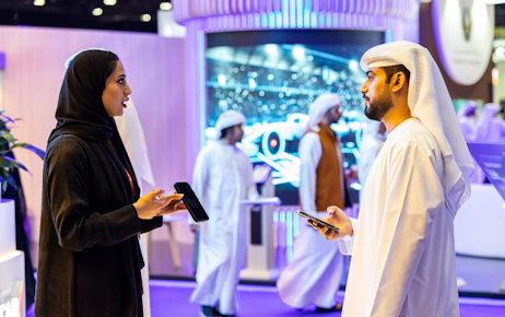 Emirati men using their phones with colleagues at Tawdheef
