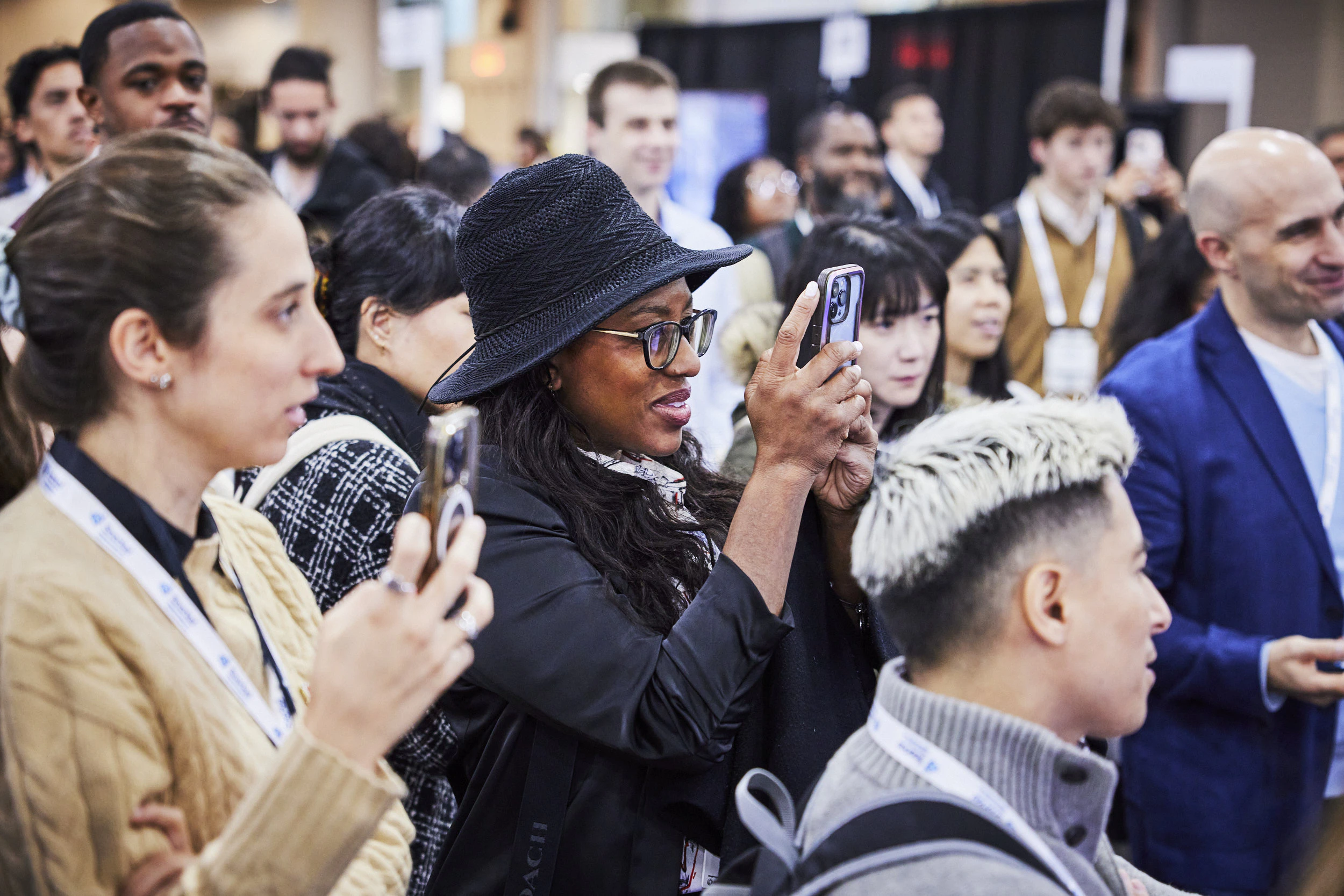 Attendees at The AI Summit take photos of content