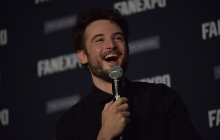 Tom Sturridge holding a microphone, laughing