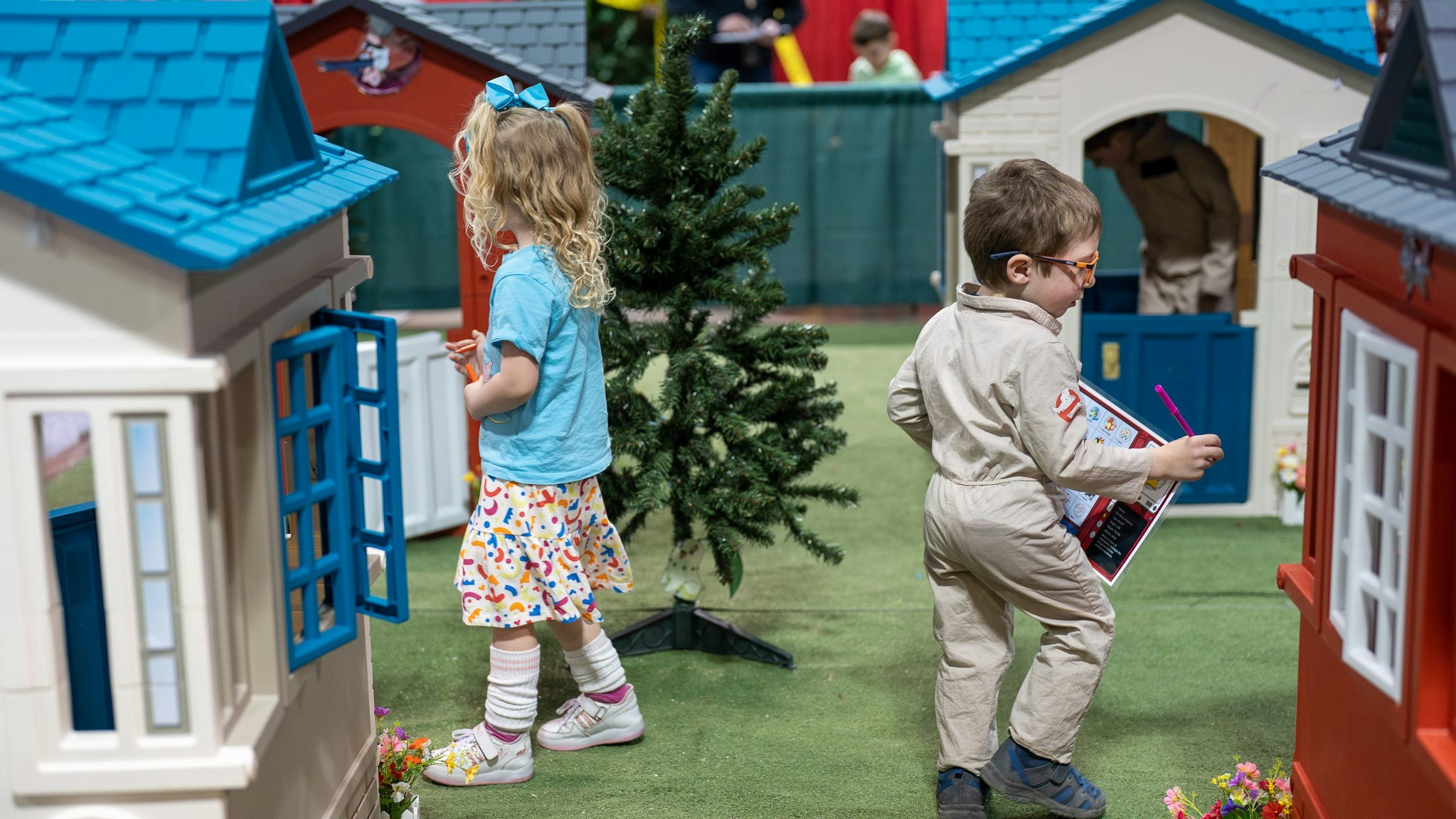 Two children are playing next to plastic houses in the family zone