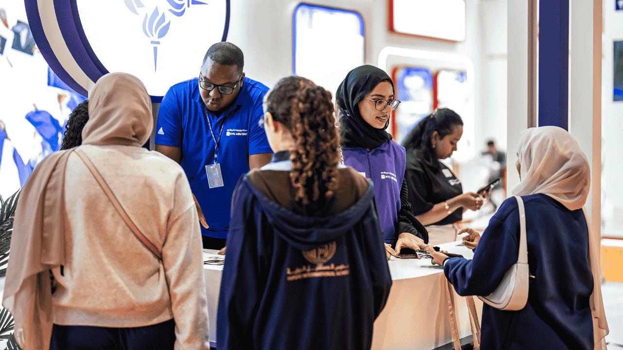 Students interacting with university admissions staff at NAJAH, receiving guidance on enrolment and programs at an engaging educational fair with diverse attendees.