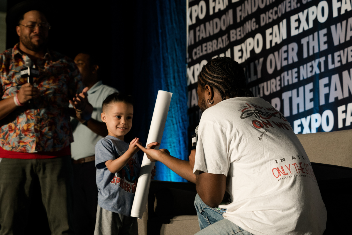 Shameik Moore at his panel with a young boy and the kid is smiling