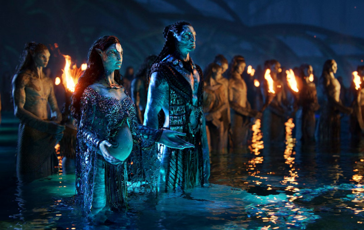A scene from the movie "Avatar: The Way of Water." Multiple Avatars are standing together in shallow water, holding torches.