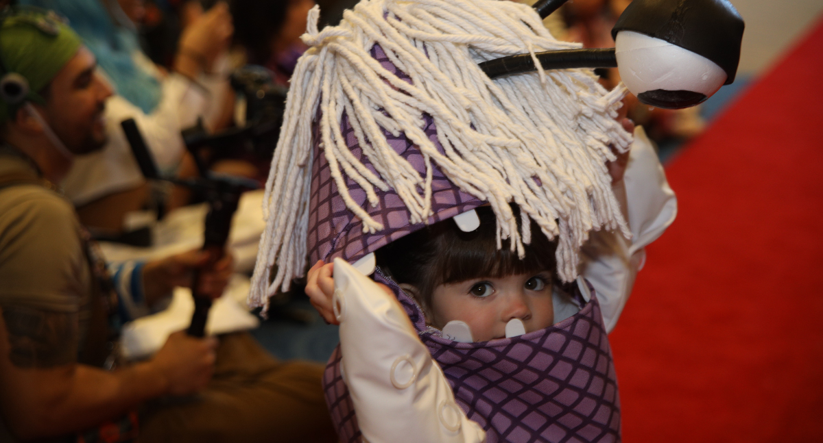 A little girl dressed up as Boo from Monster's Inc. She is wearing the homemade purple monster suit