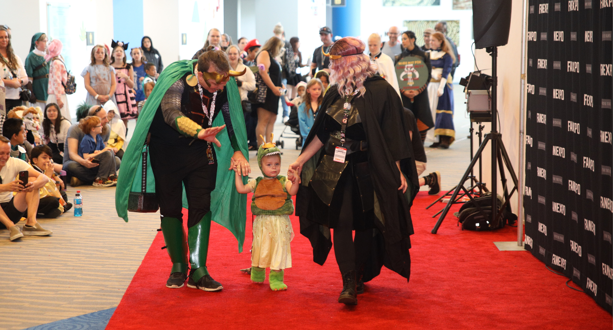 Cosplay red carpet: Dad is Loki, Mom is Sylvie, and their child is Alligator Loki! They make their way down the carpet hand in hand