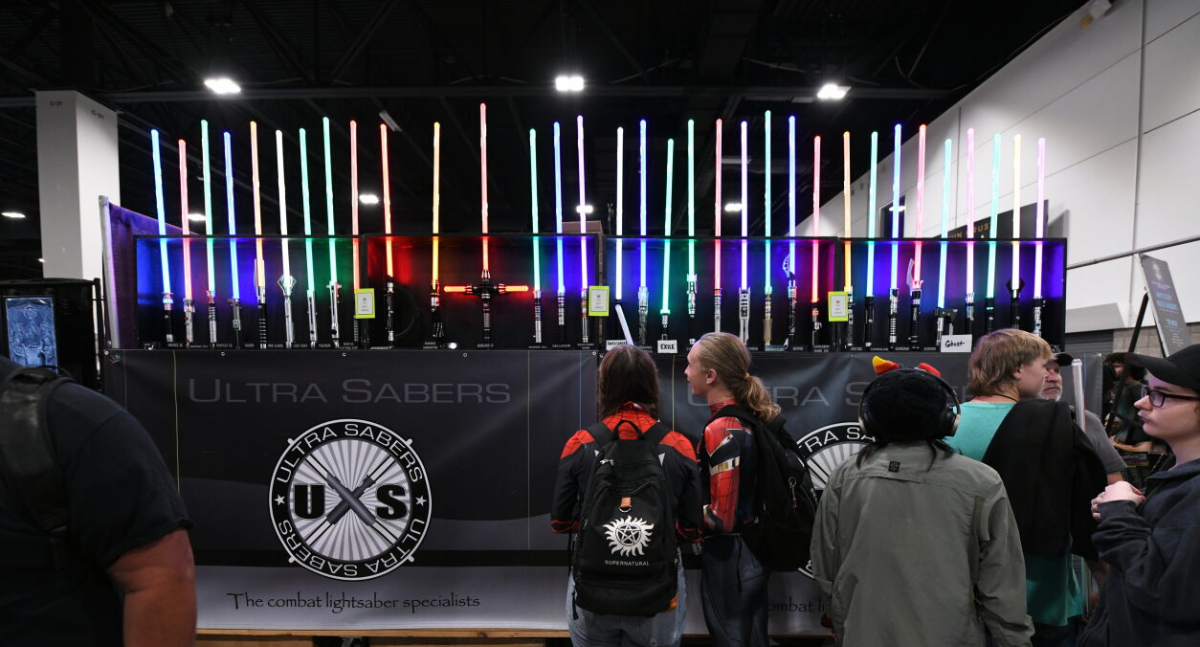 Fans browse multicoloured, illuminated light sabers at Ultra Sabers