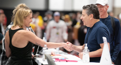 Katee Sackhoff shakes hands with an eager fan at her booth in the celebrity autograph area