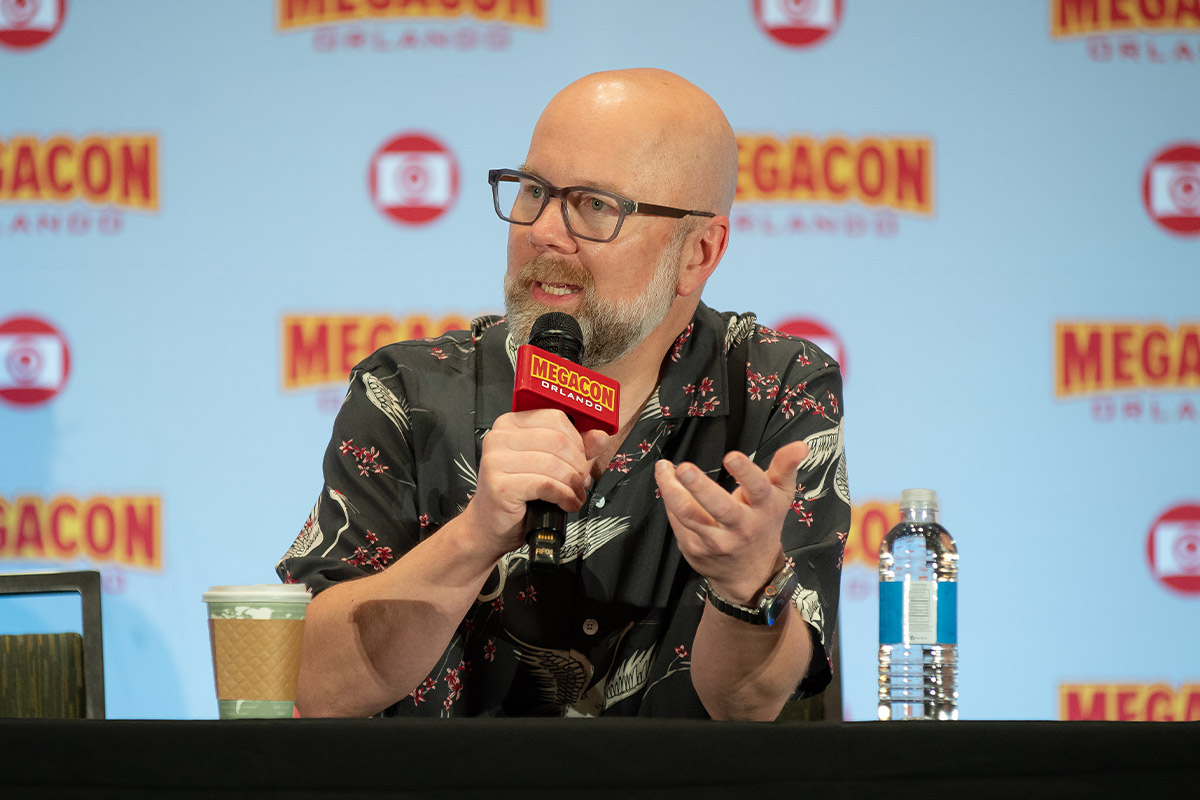 Chris Sabat gestures with his hand while speaking into a microphone
