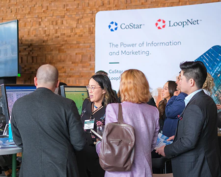 Attendees engaged at a computer screen, in conversation with one another