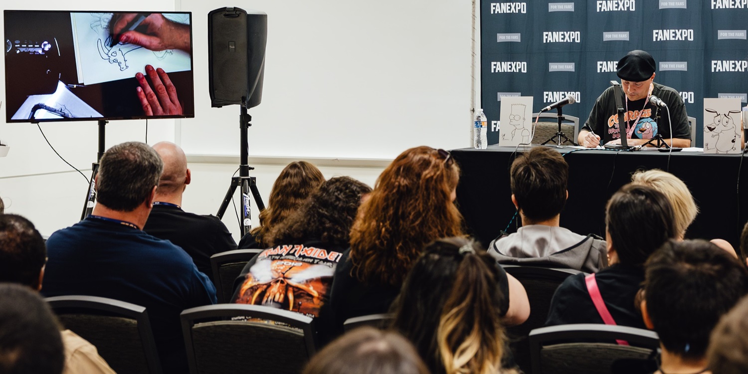 A comic artist demonstrates drawing techniques on a screen in front of a captivated audience during a live workshop at a convention. Fans watch closely as the artist brings their illustration to life.