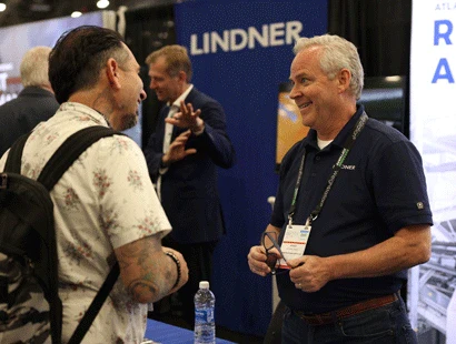 Exhibitor at his booth discussing products with an attendee