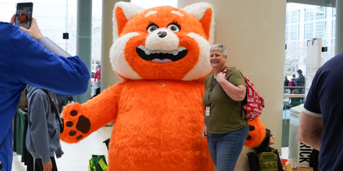 Mei Mei came in her red panda form for a meet and greet! The large red panda suit stands by the pillar, as a fellow fan takes a photo with her.