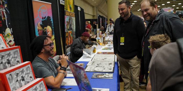 Fans chat with comic creator John Delaney in Comic Alley. Everyone is all smiles.