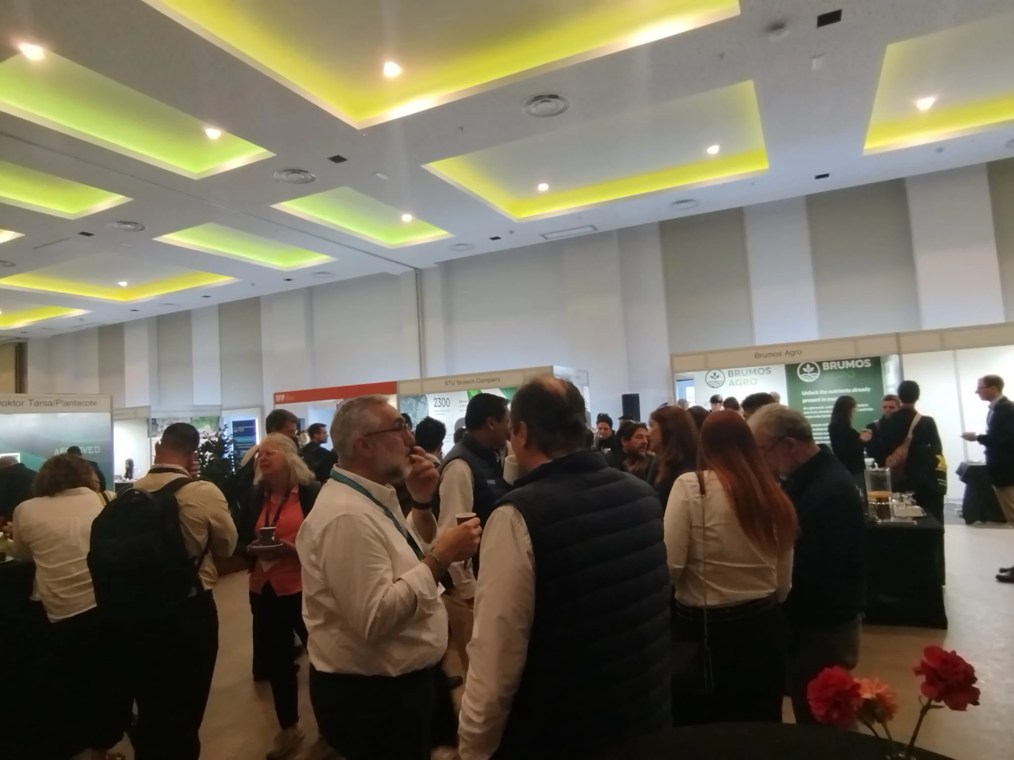 Industry professionals network at an exhibition booth at the New Ag International Annual, discussing BioAg solutions and plant nutrition innovations.