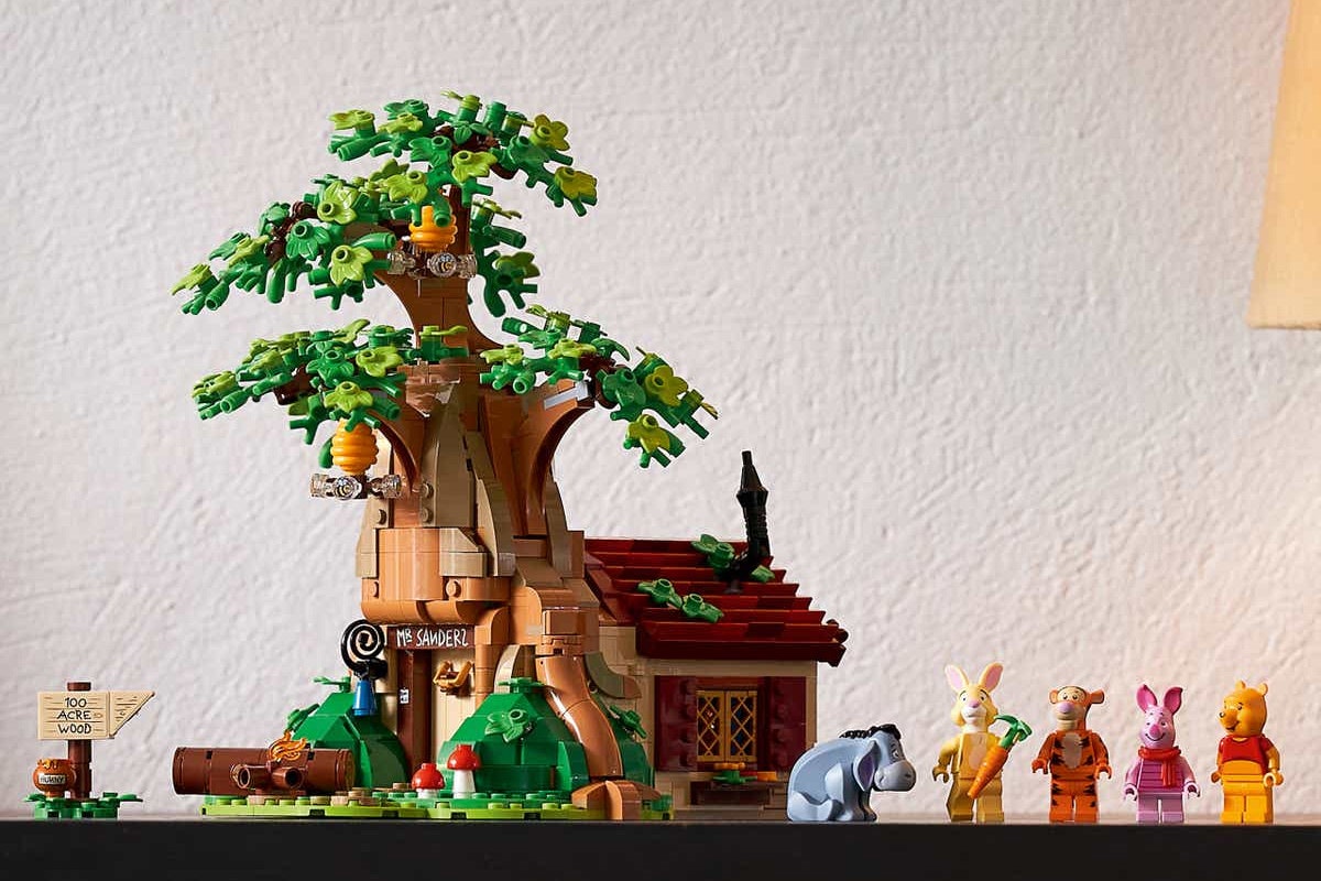 A tree Lego set with a house in it. There is Tigger, Piglet, Winnie the Pooh and Eeyore having a picnic with honey. Rabbit is coming through the door to join the fun.