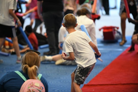 A young child readies to head into the fray for our red carpet lightsaber battle as his mother takes a photo