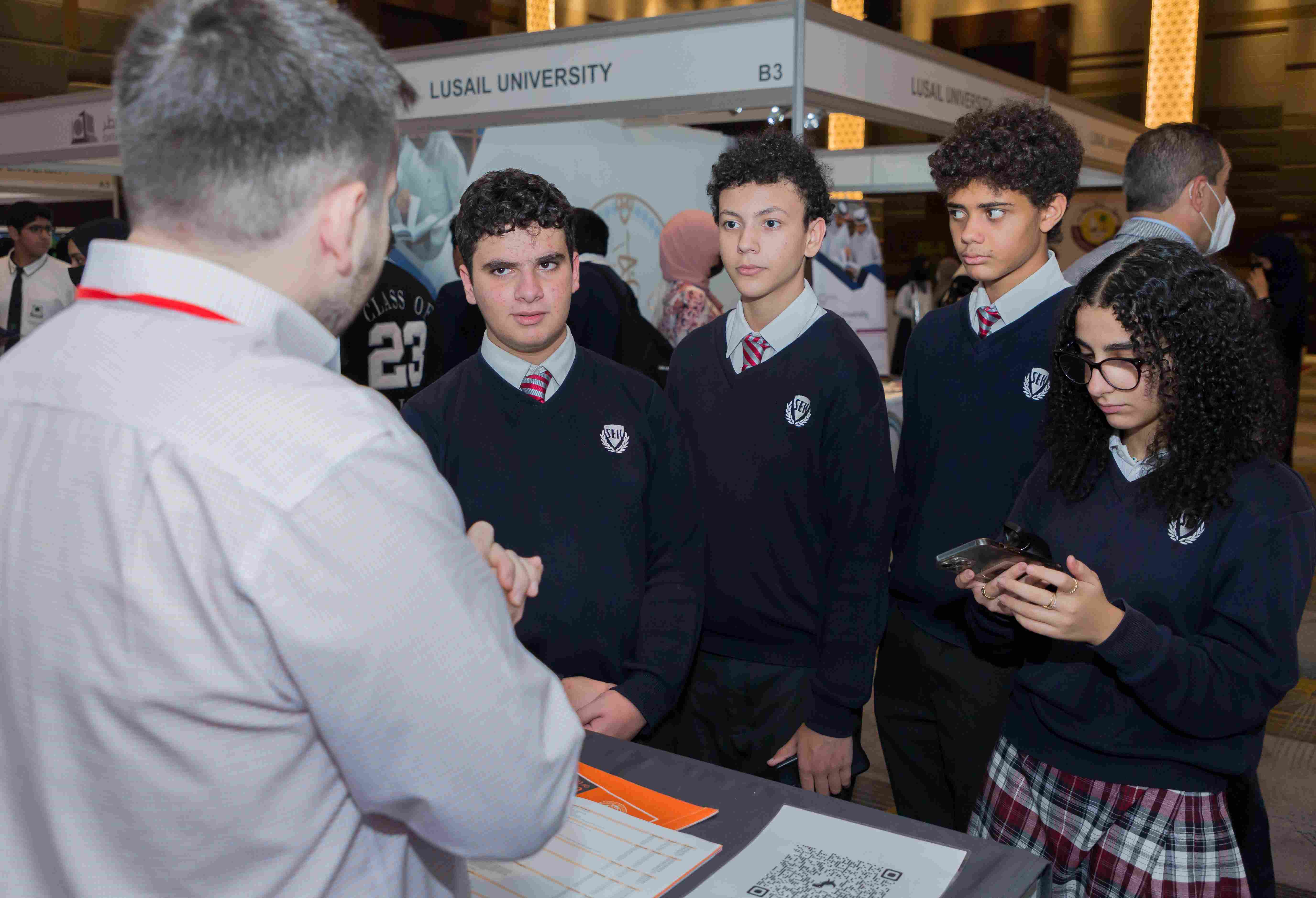 Students in school uniforms meet with a university representative at Najah Doha, Qatar’s leading higher education fair.